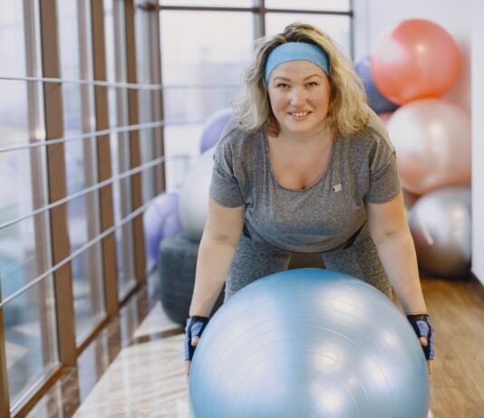 Twój pierwszy trening grupowy: jak przełamać nieśmiałość i odnaleźć się w sportowej społeczności Kobieta ćwicząca na piłce fitness w grupowej sali treningowej